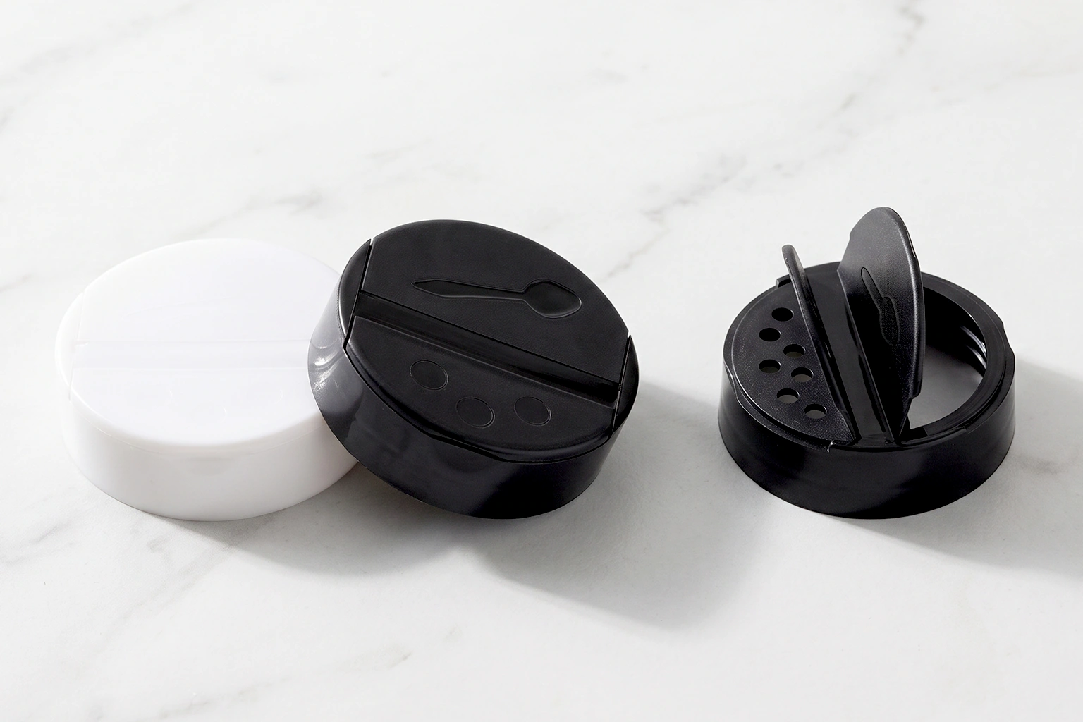 Black dual-flapper spice caps shown closed and open beside a white liner