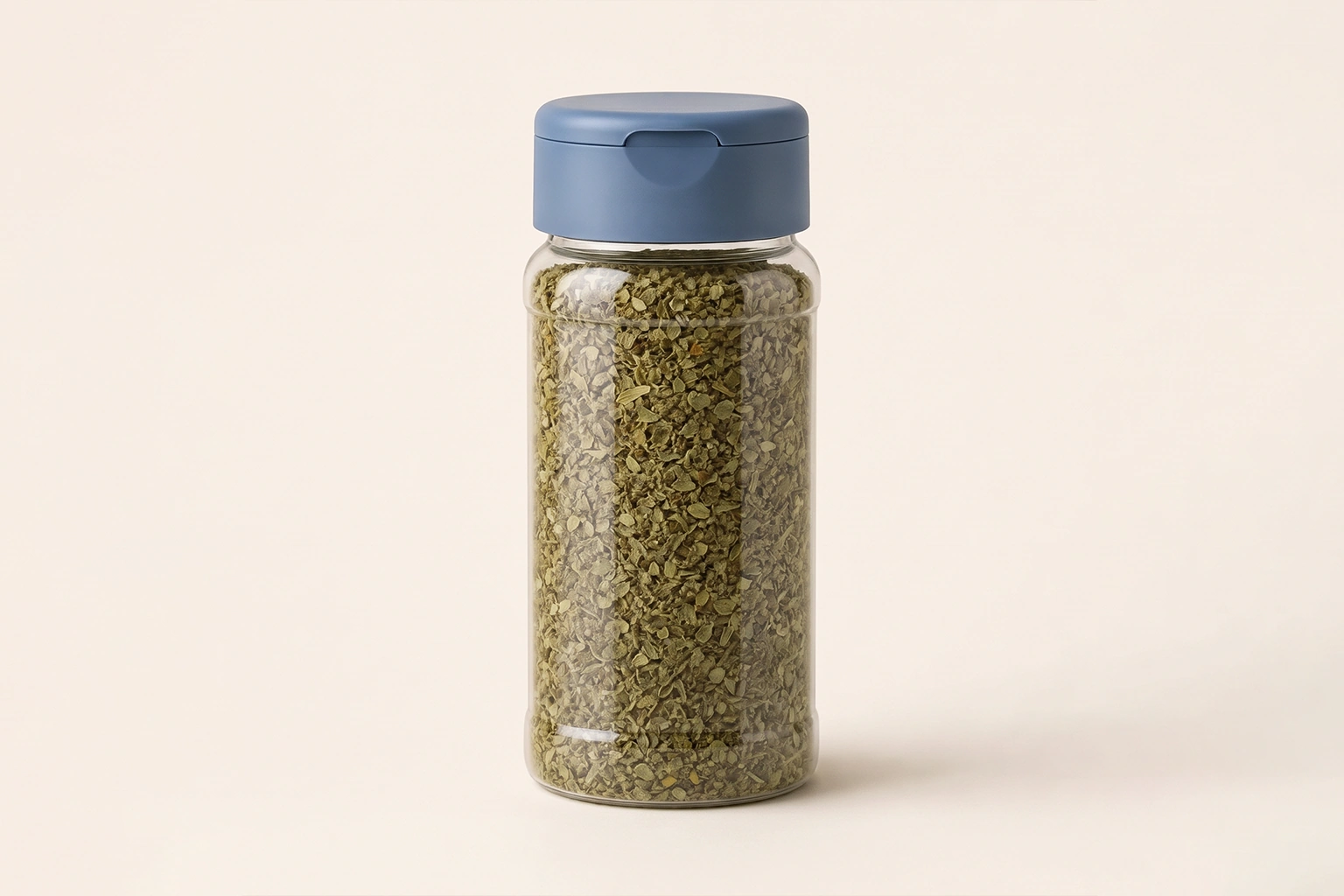 Round clear plastic spice bottle filled with dried herbs and fitted with a closed blue cap